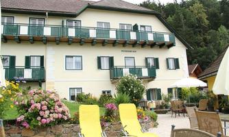 A cozy hotel with a colorful flower bed and patio furniture. Yellow deck chairs are in the foreground for relaxation.