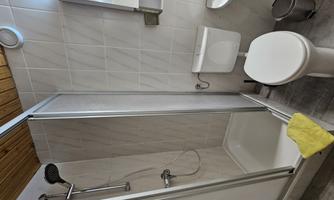 A modern bathroom with a shower, a toilet, and a sink. The walls are tiled in a light color and the furnishings are functional.