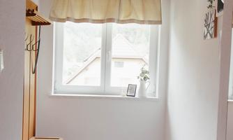 A bright entrance area with a window and a wooden shelf. It is minimally furnished and has a cozy rug.