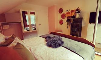 A cozy bedroom with two beds, a modern TV corner, and decorative elements on the wall. The room is bright and inviting, with soft color tones.