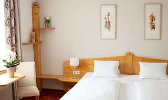 A cozy bedroom with a double bed and two pillows. The room is brightly lit and has a relaxed atmosphere.