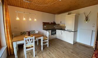 A modern kitchen with a dining table and chairs. The walls are bright, and wooden details create a cozy atmosphere.