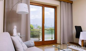 A bright living room with a sofa and a glass table. Large windows offer a view of the landscape and nature outside.