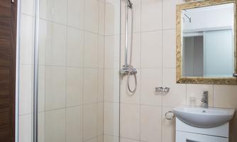 A modern bathroom with a glass shower and a hand wash basin. The walls are brightly tiled and there is a mirror above the sink.
