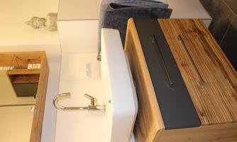 A modern bathroom with a white sink on a wooden cabinet. Towels and decorations complement the elegant design.