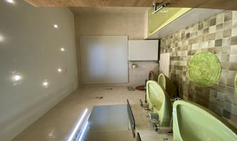 A modern bathroom with green sinks and a bathtub. The walls are painted in neutral colors and there is bright lighting.