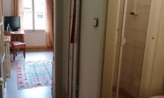 A bright hallway with access to a bathroom and a living room. In the background, a television and a carpet are visible.