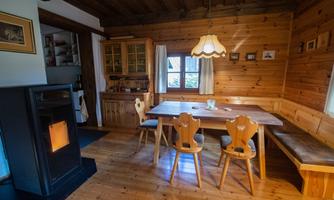 A cozy room with wooden walls and a large table. A fireplace creates a warm atmosphere.
