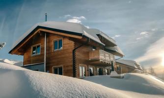 A cozy wooden house, surrounded by deep snow. The sky is clear and the sun is shining.