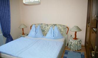 A cozy bedroom with a double bed and two charming nightstands. The room is decorated in soft colors and has curtains that gently filter the light.