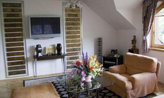 A cozy living room with a television on the wall and an oval glass table. Comfortable armchairs and a beautiful bouquet create an inviting atmosphere.