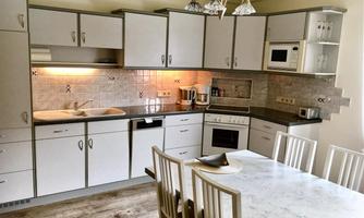 A modern kitchen with white cabinets and a sleek countertop. At the table are chairs that create an inviting atmosphere.