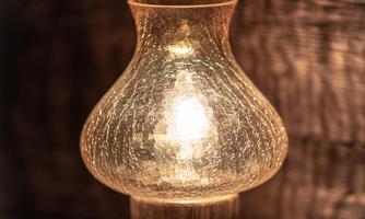 A beautiful lamp with a glass lampshade that emits warm light. The background is soft and slightly blurred.