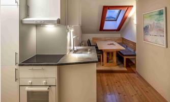 A bright, modern kitchen with a table and benches in a cozy dining area. Large skylights provide plenty of light in the room.