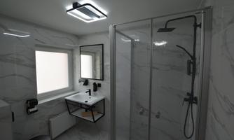 A modern bathroom with a glass door shower and an elegant sink. Bright walls with marble effect create a stylish atmosphere.