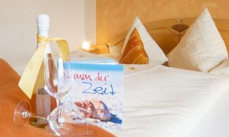 A beautifully decorated bed with fresh pillows and a bottle of champagne. There are also glasses and a card with the inscription "Take your time."