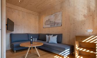 A cozy living room with wood-paneled walls. There is a sofa, a small table, and a TV corner.