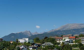 A picturesque landscape with mountains in the background and a tranquil settlement in the foreground. The clear blue sky makes the idyll shine.