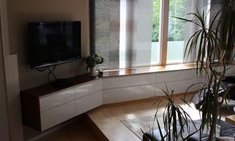 A modern living space with a television, a spacious windowsill, and plants. Bright colors and plenty of natural light create an inviting atmosphere.