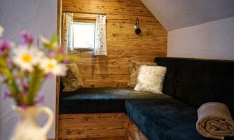 A cozy living area with wooden paneling and a comfortable seating arrangement. On the table, there is a vase with colorful flowers that give the room a fresh atmosphere.