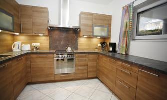 A modern kitchen with wooden furniture and a large stove. The walls are bright and there is plenty of countertop space.