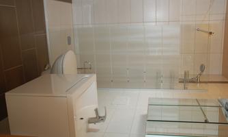 A modern bathroom with a shower cubicle and a sink. The walls are painted in light colors and the floor is tiled in dark shades.