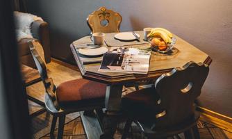 A cozy table with a fruit bowl and two plates in a stylish room. On the table lies a magazine and a cup of coffee.