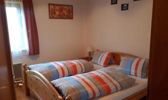 A cozy bedroom with two beds and checkered blankets. Pictures hang on the wall and the room has a friendly atmosphere.