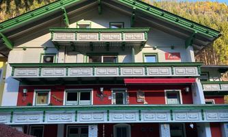 A multi-storey building with a green roof and colorful paint. It has several balconies and is situated in a mountainous area.