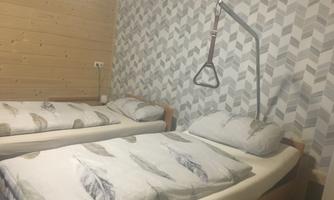 A bedroom with two beds and a modern, geometric pattern on the wall. A support device is installed next to one of the beds.
