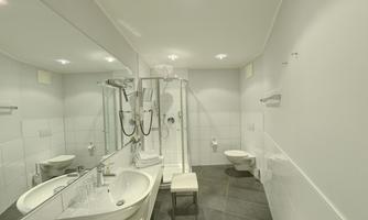 A modern bathroom with white tiles and a large mirror. There is a shower, a sink, and a toilet.