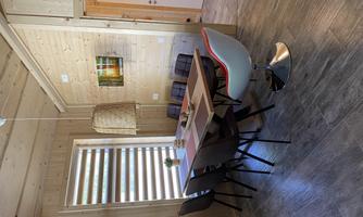 A modern dining area with a large table and several chairs. The walls are made of light wood and the lighting is friendly and inviting.