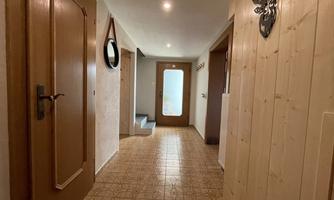 A bright hallway with wood paneling and a large window. A mirror and decorative elements are hanging on the wall.