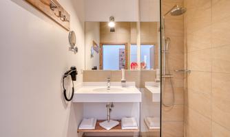 A modern bathroom with a shower and an elegant sink. The walls are in warm beige and earth tones.