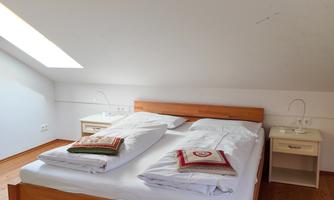 A bright bedroom with a double bed and clean white bedding. Next to the bed are two nightstands.