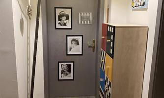 A modern entrance area with gray walls and a red carpet. Four black-and-white pictures hang on the wall.