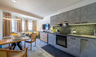 A modern apartment with an open kitchen and living area. The space is bright and inviting, with large windows and stylish furniture.