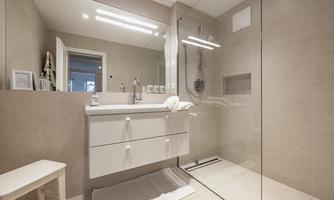 A modern bathroom with a spacious shower and an elegant sink. The walls are painted in neutral colors, creating a bright and clear atmosphere.