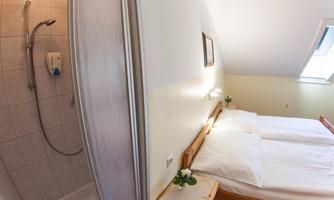 A cozy bedroom with two beds and soft colors. On the left side, there is a shower.