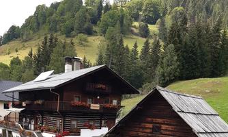 A picturesque mountain landscape with traditional wooden houses. In the background, green forests and gentle hills can be seen.