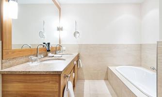 A modern bathroom with a bathtub and a large mirror. The walls are designed in a light and elegant manner.