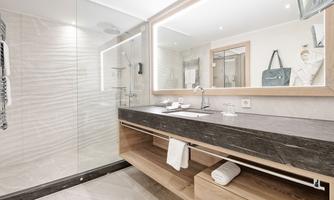 A modern bathroom with an elegant shower and a wooden vanity. The lighting creates a pleasant atmosphere.