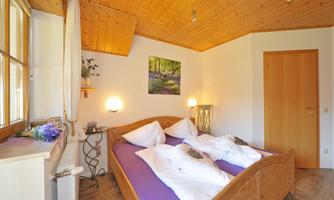 A cozy bedroom with wooden decor. There is a large bed with white pillows and a picturesque wall decoration.