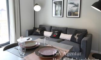 A cozy living room with a gray sofa and decorative cushions. The table is nicely set with dishes and glasses.