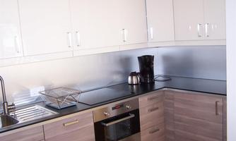 Modern kitchen with bright cabinets and black countertops. A coffee machine and a sink are also visible.
