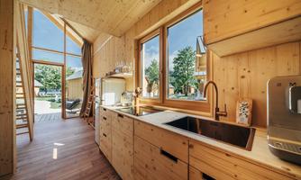 A modern wooden kitchen with large windows and plenty of natural light. The room is bright and invitingly designed.