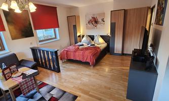 A cozy bedroom with a double bed and modern furniture. The walls are adorned with artwork and large windows let in plenty of light.