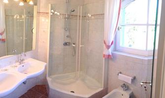 A modern bathroom with a glass shower and a double sink. The soft lighting and bright colors create an inviting atmosphere.