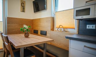 A modern kitchenette with a wooden dining area. A small vase with flowers is placed on the table.