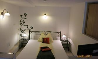 A simple bedroom with a double bed and two nightstands. The walls are painted in light colors and there are some decorative lights.